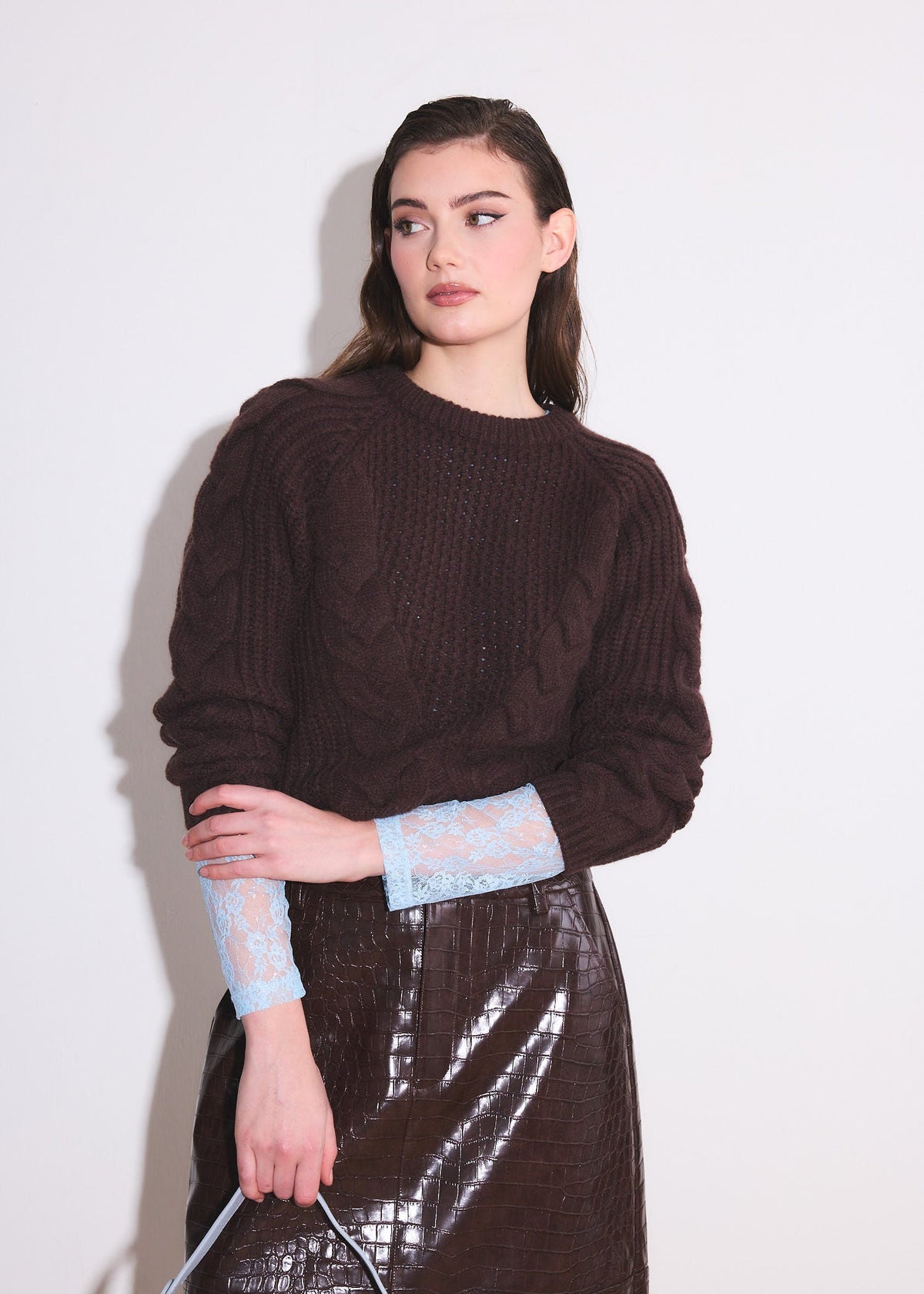 model wearing a brown cable knit sweater with blue lace shirt underneath 